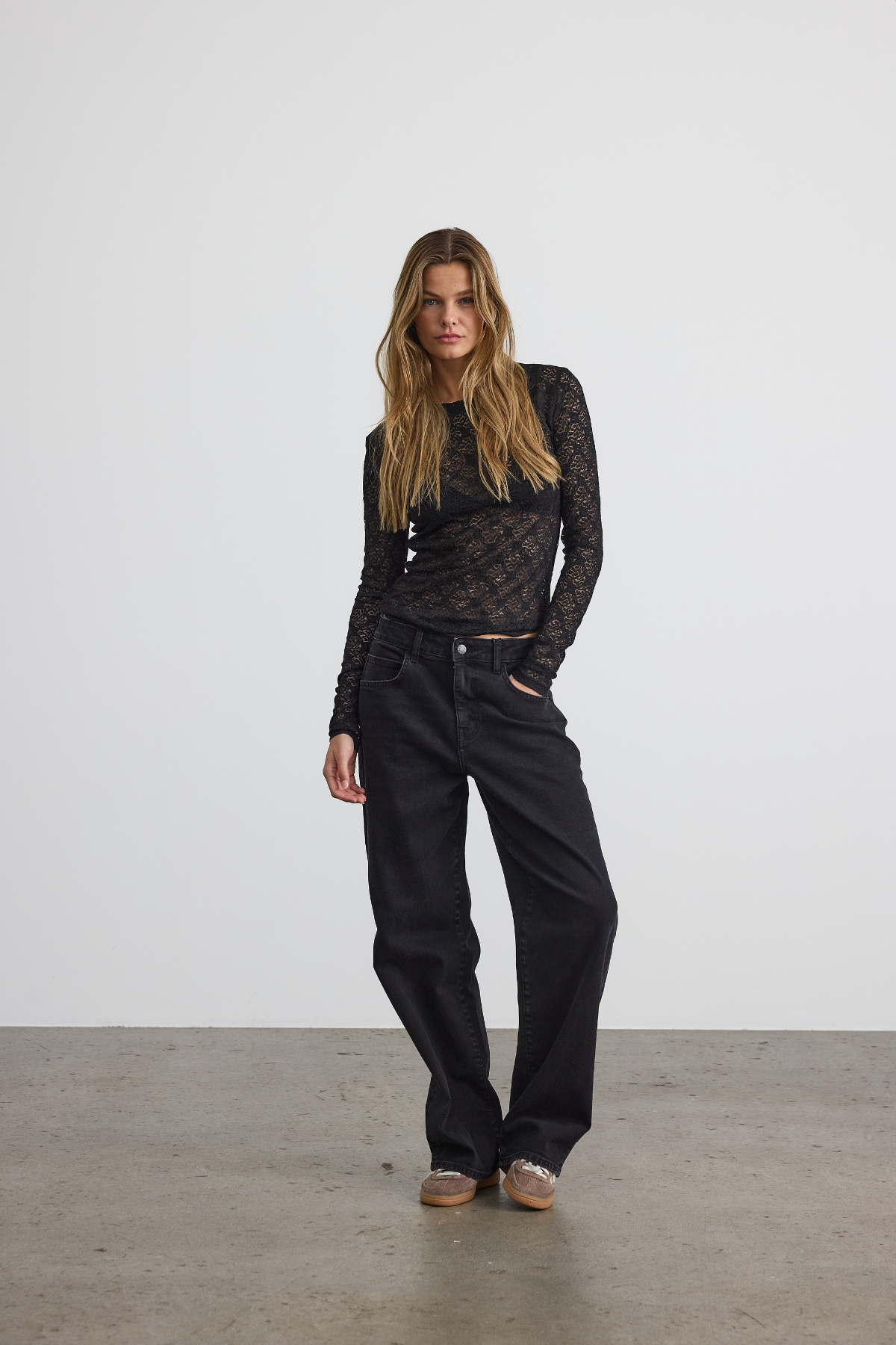 Studieoptagelse af blondetop stylet med sorte jeans og sneakers – cool og afslappet vibe