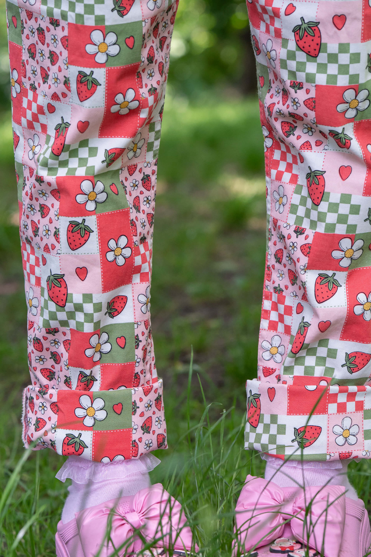Nærbillede af buksebenet på Strawberry Picnic Dungarees, rullet op og stylet med pink sko.