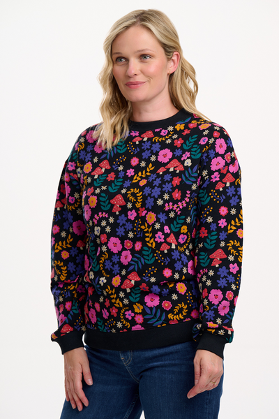Blond model i sweatshirt fra Sugarhill Brighton – sort bund med blomster og svampeprint i pink, lilla og gul.