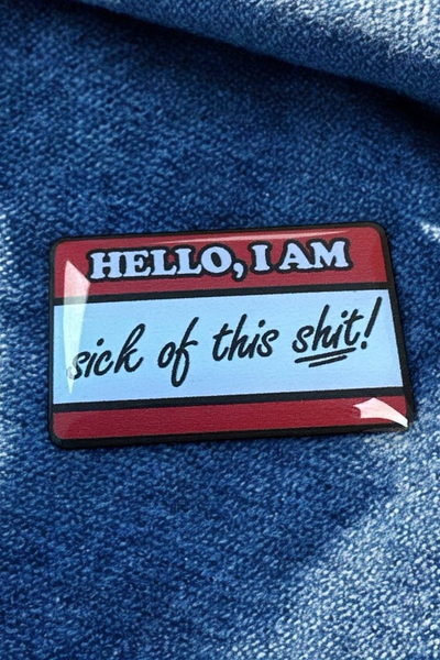Pin fastgjort på blåt denimstof, fotograferet tæt på i sollys.