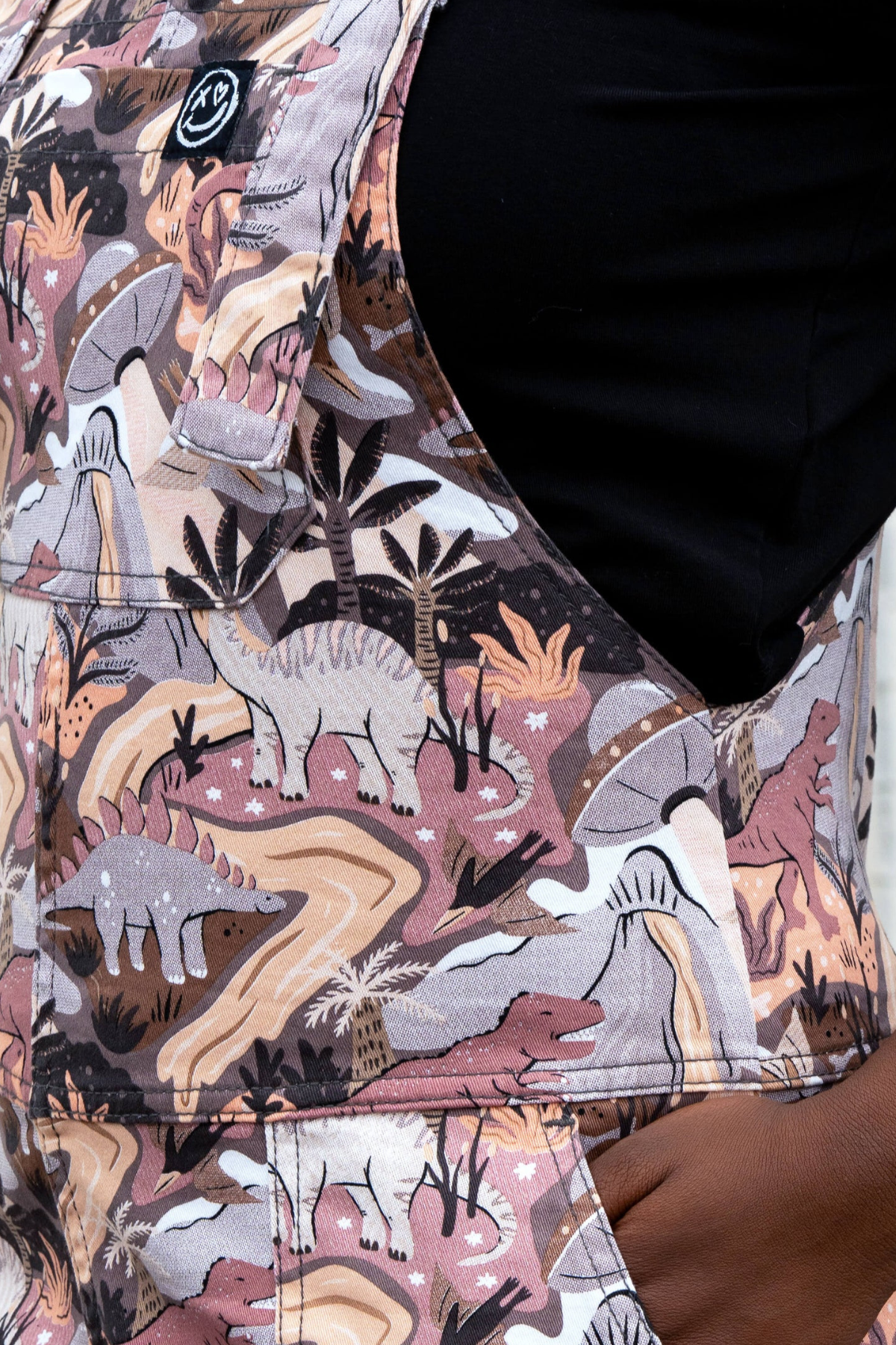 Close-up af Rebel Romance Dinoverse stof med håndtegnet dinosaur-, palme- og vulkanprint i jordtoner.