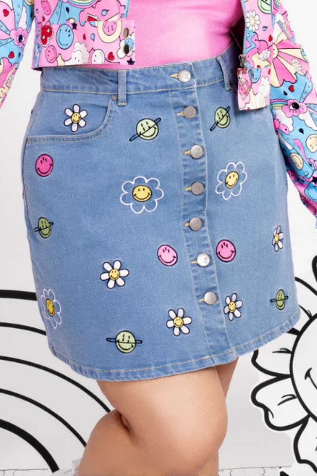 A-formet denimnederdel med farverigt Smiley-ansigt og planetbroderi, knaplukning foran og lommer.
