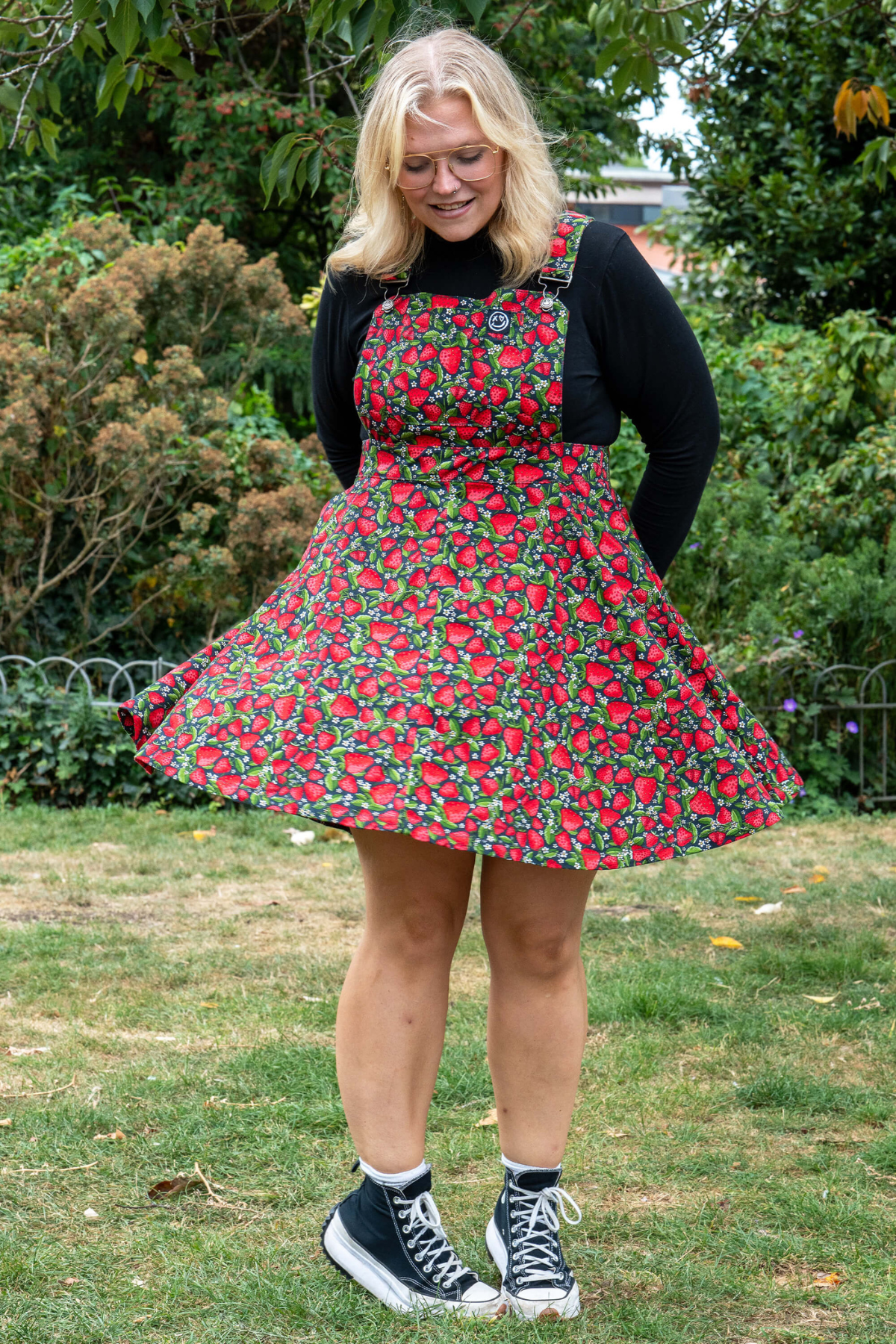 Model i Rebel Romance Strawberry Field Pinafore med farverigt jordbærprint og sort bluse.