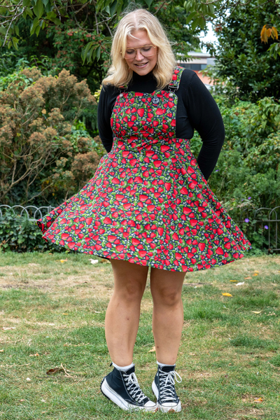 Model i Rebel Romance Strawberry Field Pinafore med farverigt jordbærprint og sort bluse.