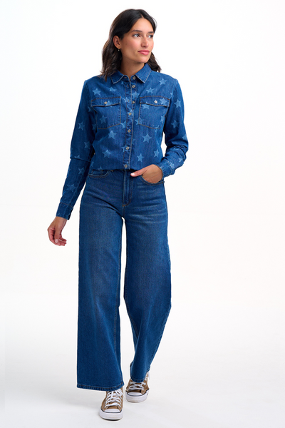 Model iført ALEXIA denimskjorte med stjerner og blå wide-leg jeans, stående i fuld figur.