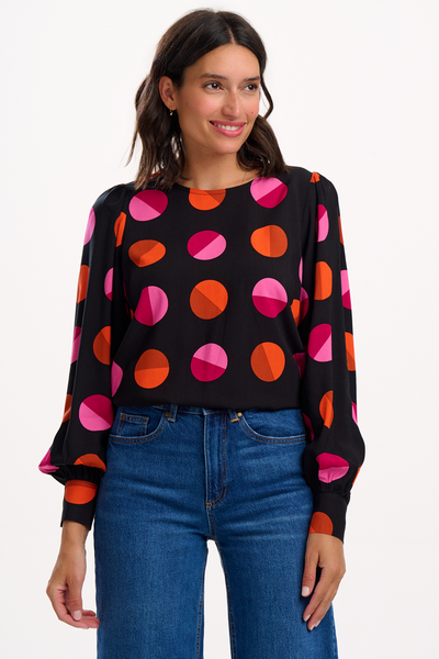 Model iført Ronnie Puff Sleeve Top med pink og orange cirkler på sort bund, stylet med jeans
