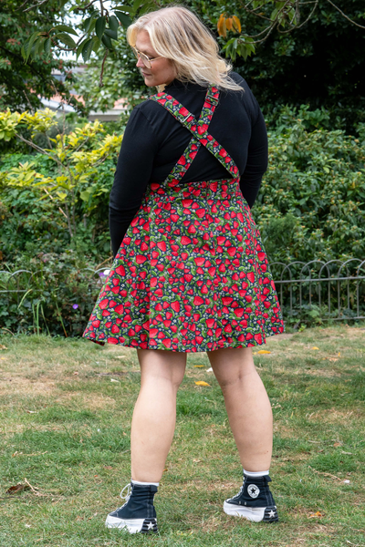 Bagfra visning af Rebel Romance Strawberry Field Pinafore med krydsede stropper og jordbærmønster.