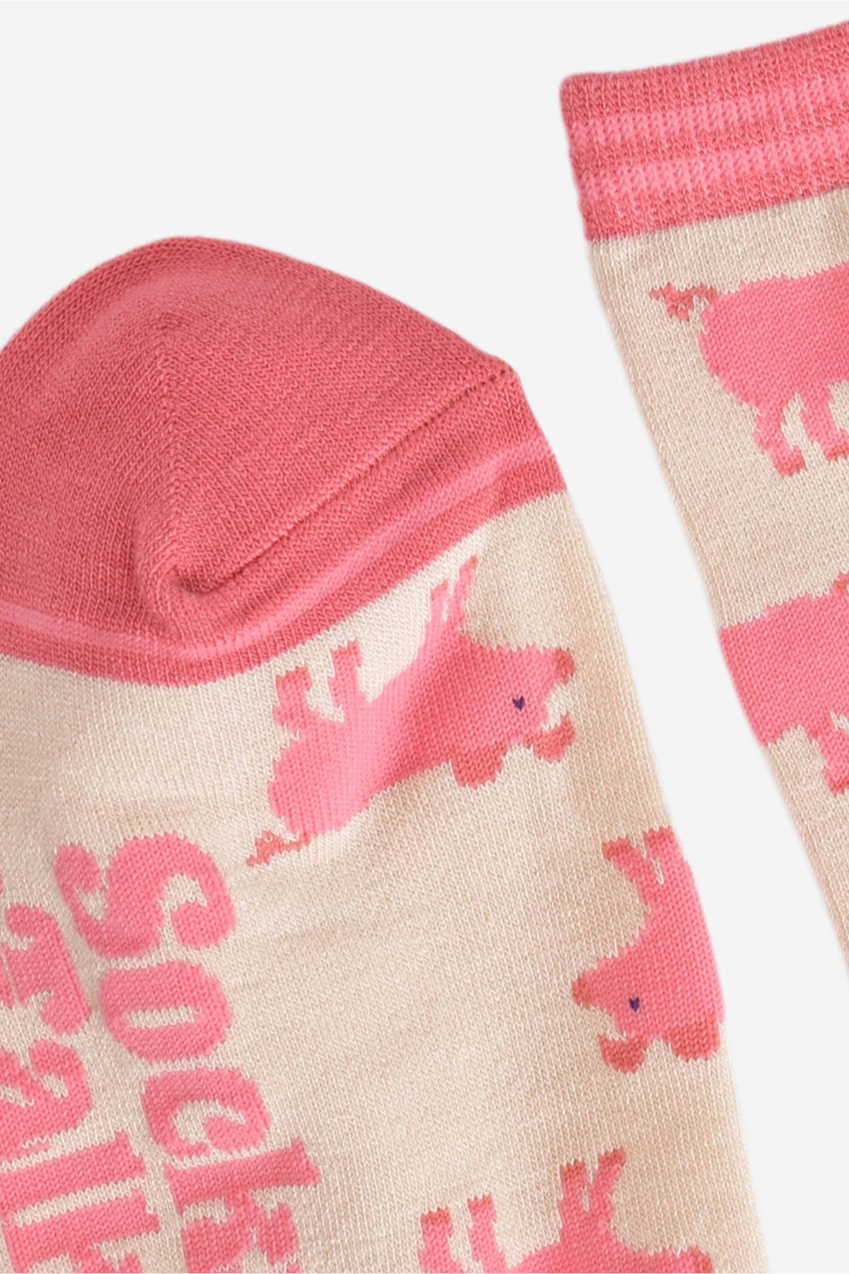 Tæt på tå og logo – detaljer i pink og beige samt grisemotiv.