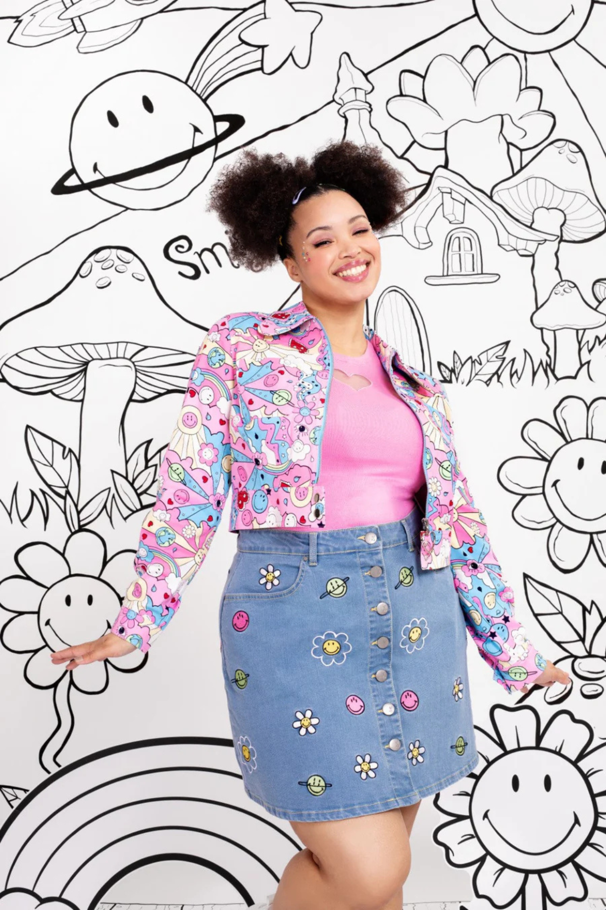 Model iført blå denimnederdel med Smiley-broderi stylet med pink top og matchende farverig jakke.