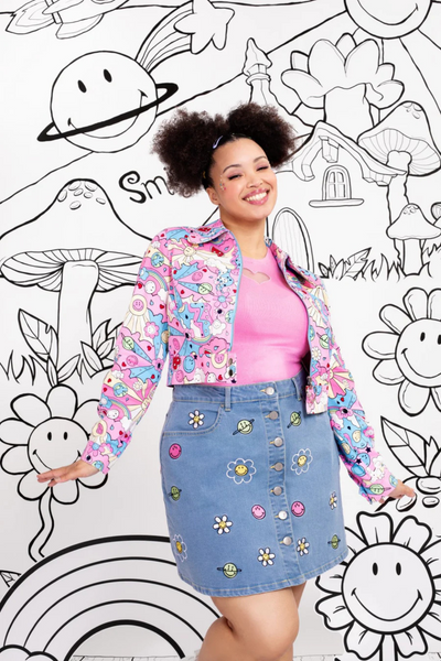 Model iført blå denimnederdel med Smiley-broderi stylet med pink top og matchende farverig jakke.