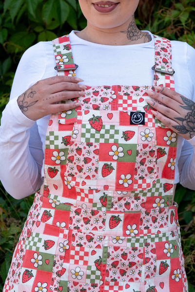 Nærbillede af Katie, der holder i selerne på smæk-kjolen – fokus på blomster- og jordbærprint samt logo