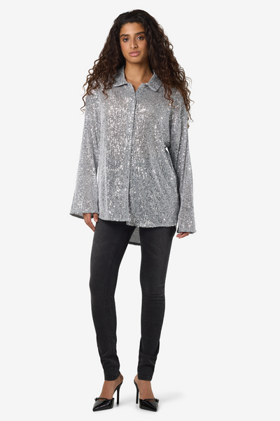 Noisy May Scarlet Sequin Shirt i sølv – fuld figur med sorte skinny jeans og hæle – festligt look.
