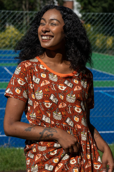 Smilende model i Mushroom Tea Party Dress – nærbillede af printdetaljer og rund hals.