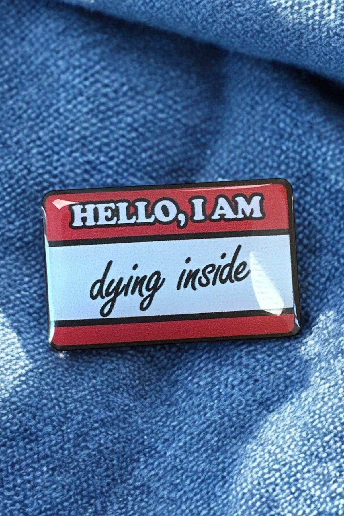 Pin fastgjort på blåt denimstof, set tæt på.
