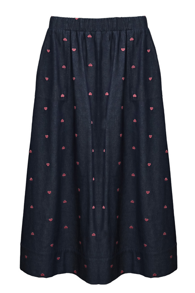 Tatum Skirt fra Costa Mani – blå denimnederdel med små lyserøde hjerter, elastisk linning og sidelommer, vist på hvid baggrund