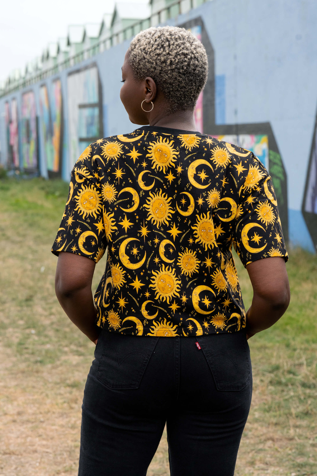 Rebel Romance Celestial Sun & Moon Tee set bagfra – all-over print med gyldne sol- og stjernemotiver.