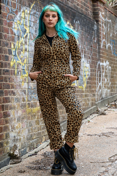 Model i Rebel Romance Leopard Boiler Suit med klassisk leopardprint og sorte støvler foran mur med graffiti.