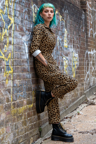 Model i Rebel Romance Leopard Boiler Suit læner sig mod mur – fokus på pasform og printdetaljer.