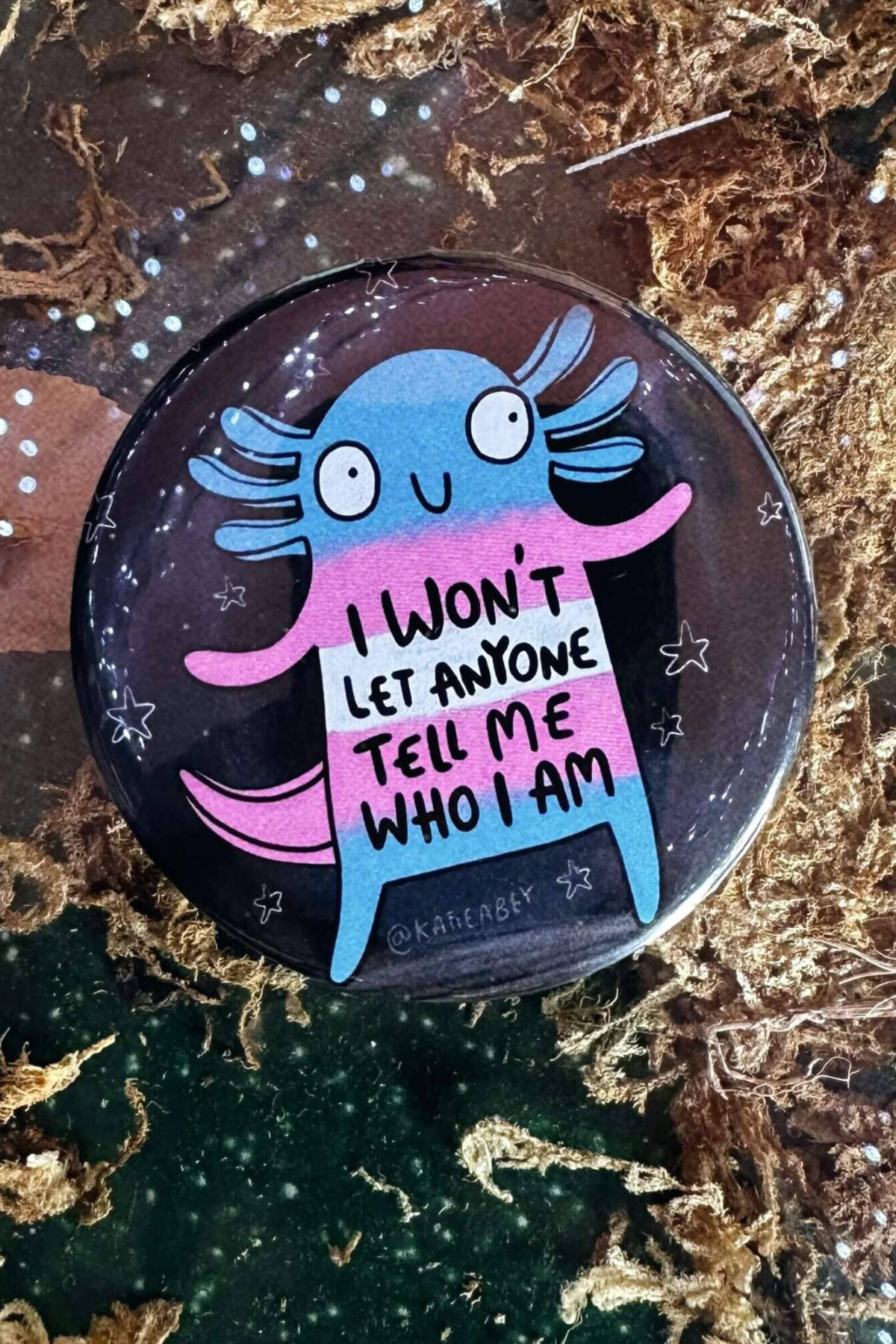 Katie Abey badge med blå og pink axolotl på mørk baggrund