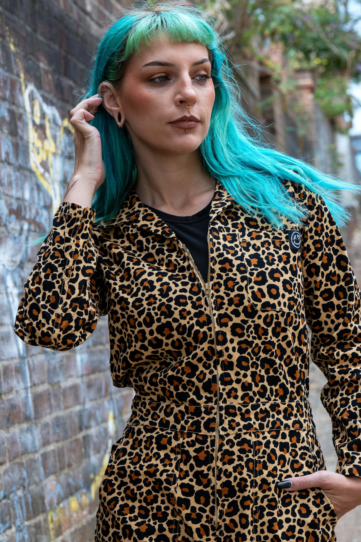 Nærbillede af model i Rebel Romance Leopard Boiler Suit med lynlås og brystlomme med logo.