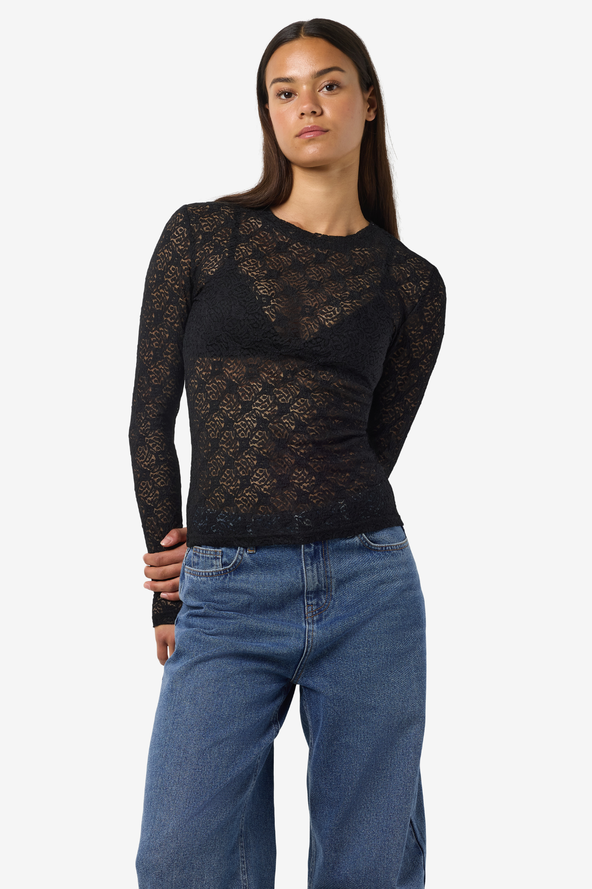 Frontvisning af sort blondebluse stylet med lyseblå jeans – gennemsigtigheden fremhæver lag-på-lag look