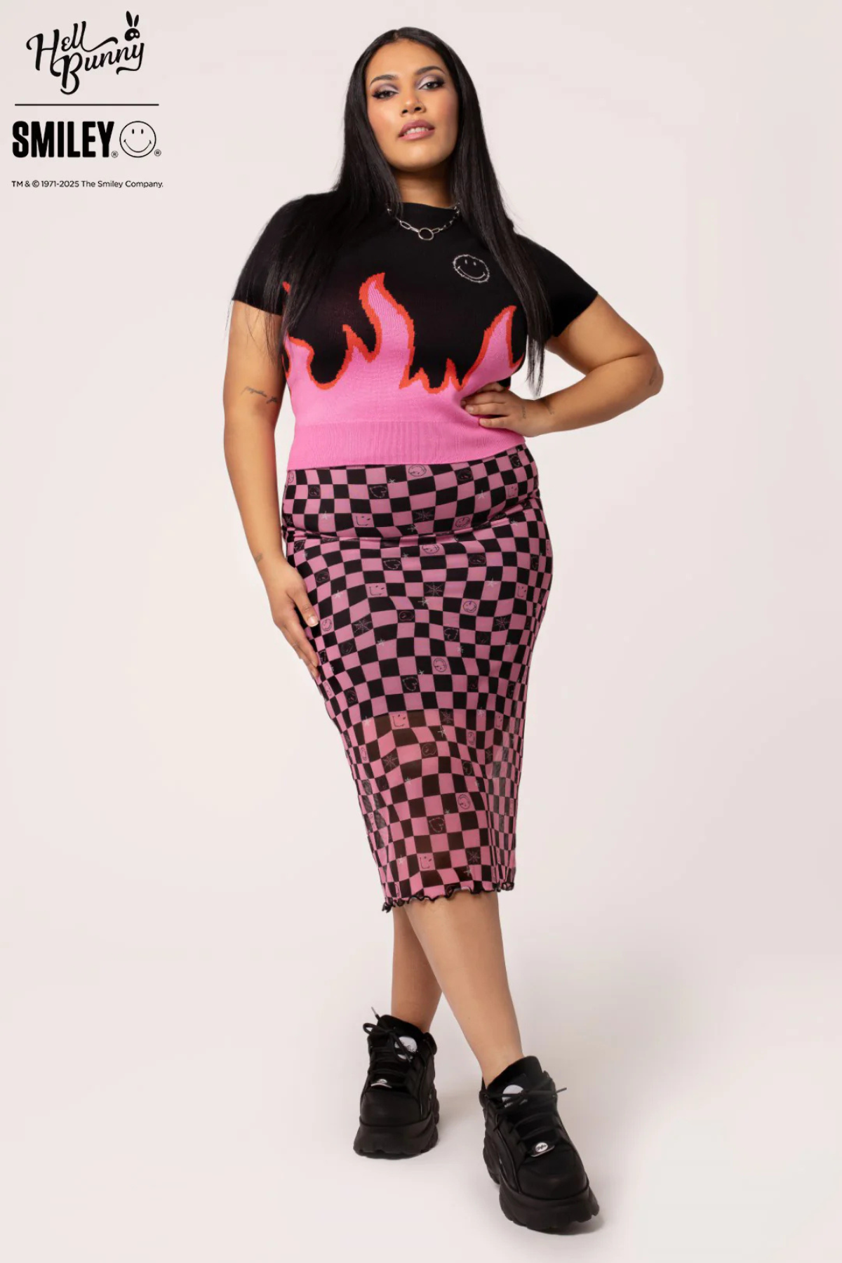 Plus size model i Distortion Skirt og Dylan Top, frontalt med begge hænder på hofterne.