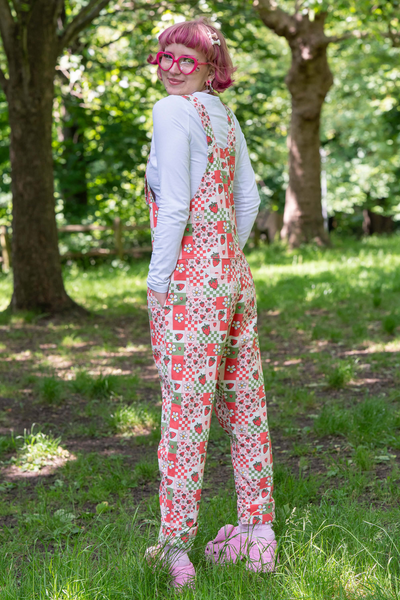 Billede bagfra af @fairyjesss i Strawberry Picnic Dungarees midt i en grøn skov.