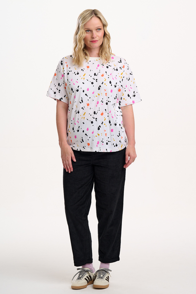 Model iført Kinsley Relaxed T-shirt med farverigt splash-print stylet med sorte bukser og sneakers.