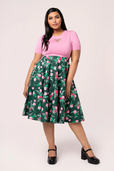 Plus size model iført Hell Bunny Mabel Skirt – grøn 50’er nederdel med pink blomsterprint, stylet med pink top