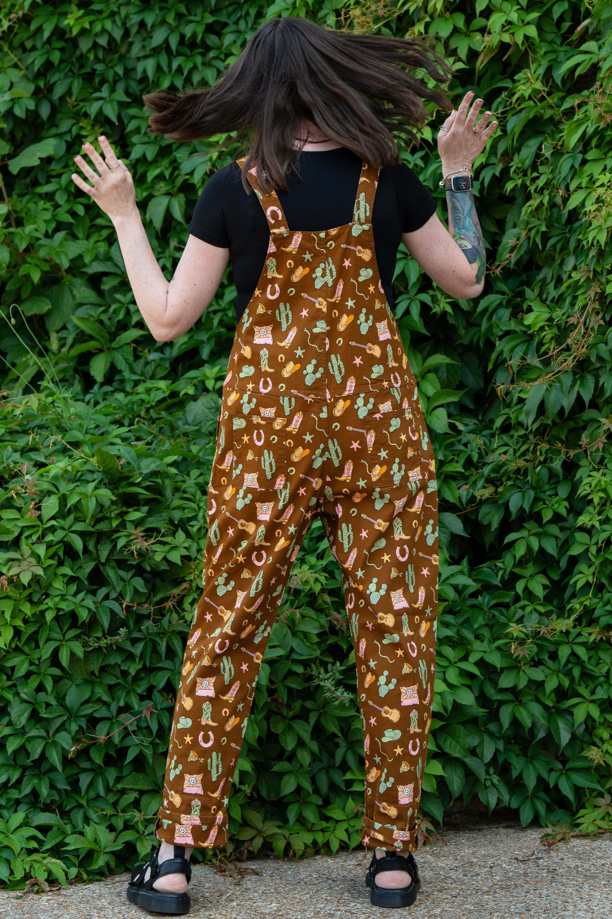 Rebel Romance x Yasmin Cousins Cowboy Dungarees vist bagfra. Brunt stof med western motiver og justerbare seler.