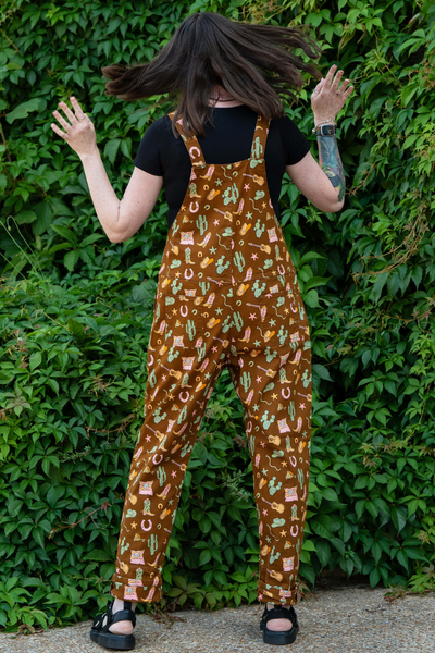 Rebel Romance x Yasmin Cousins Cowboy Dungarees vist bagfra. Brunt stof med western motiver og justerbare seler.