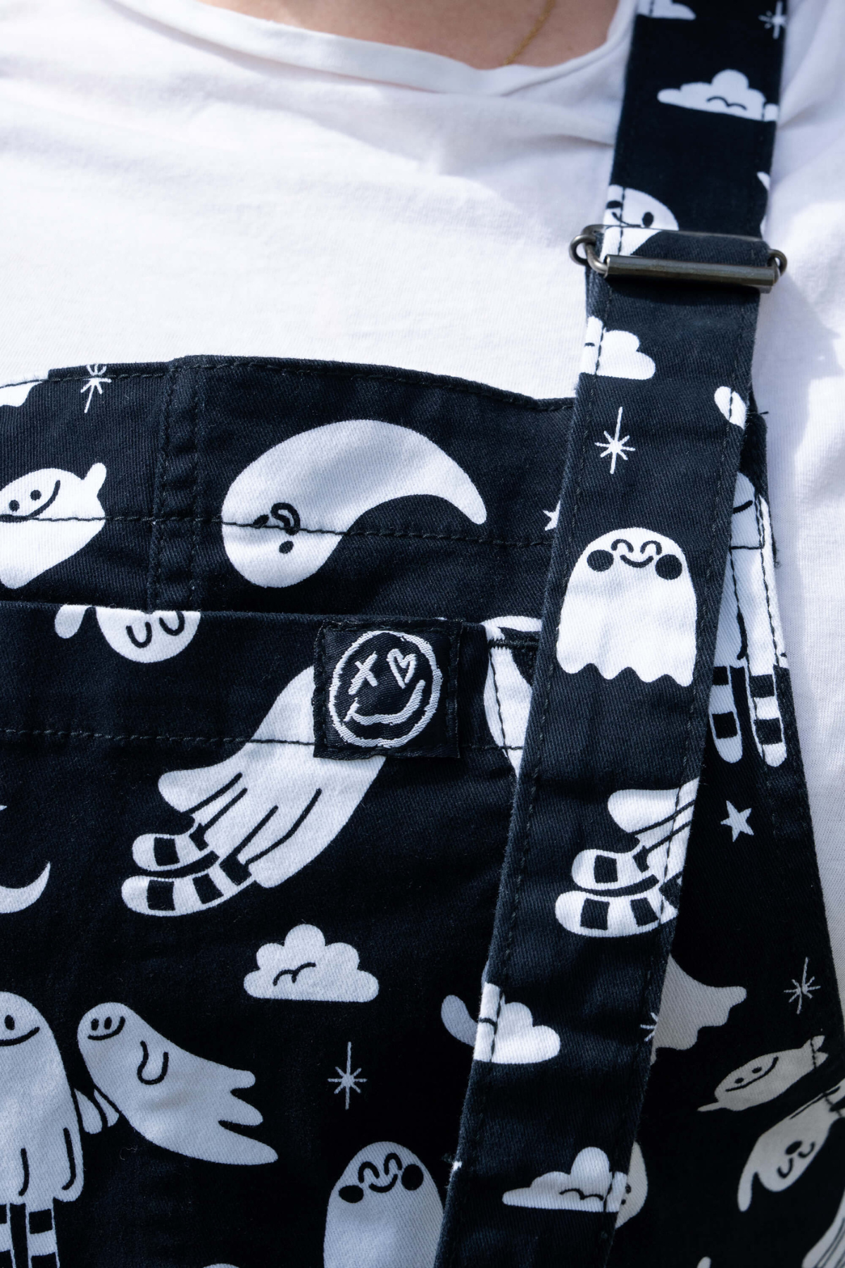Nærbillede af frontlomme og Rebel Romance-logo på Ghosties Dungarees med hvidt spøgelsesprint.