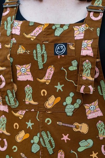 Rebel Romance smiley-logo og printdetaljer på cowboy dungarees – Yasmin Cousins design.