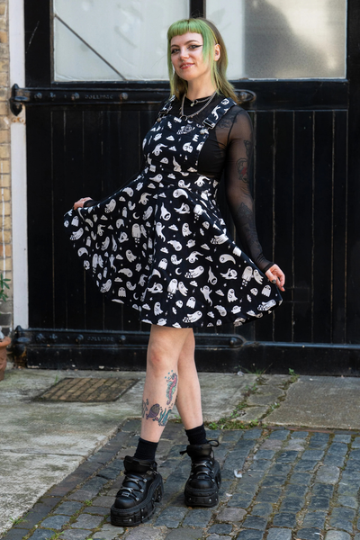 Model iført Rebel Romance x Yasmin Cousins Ghosties Flared Pinafore. Sort kjole med spøgelsesprint og flared nederdel.