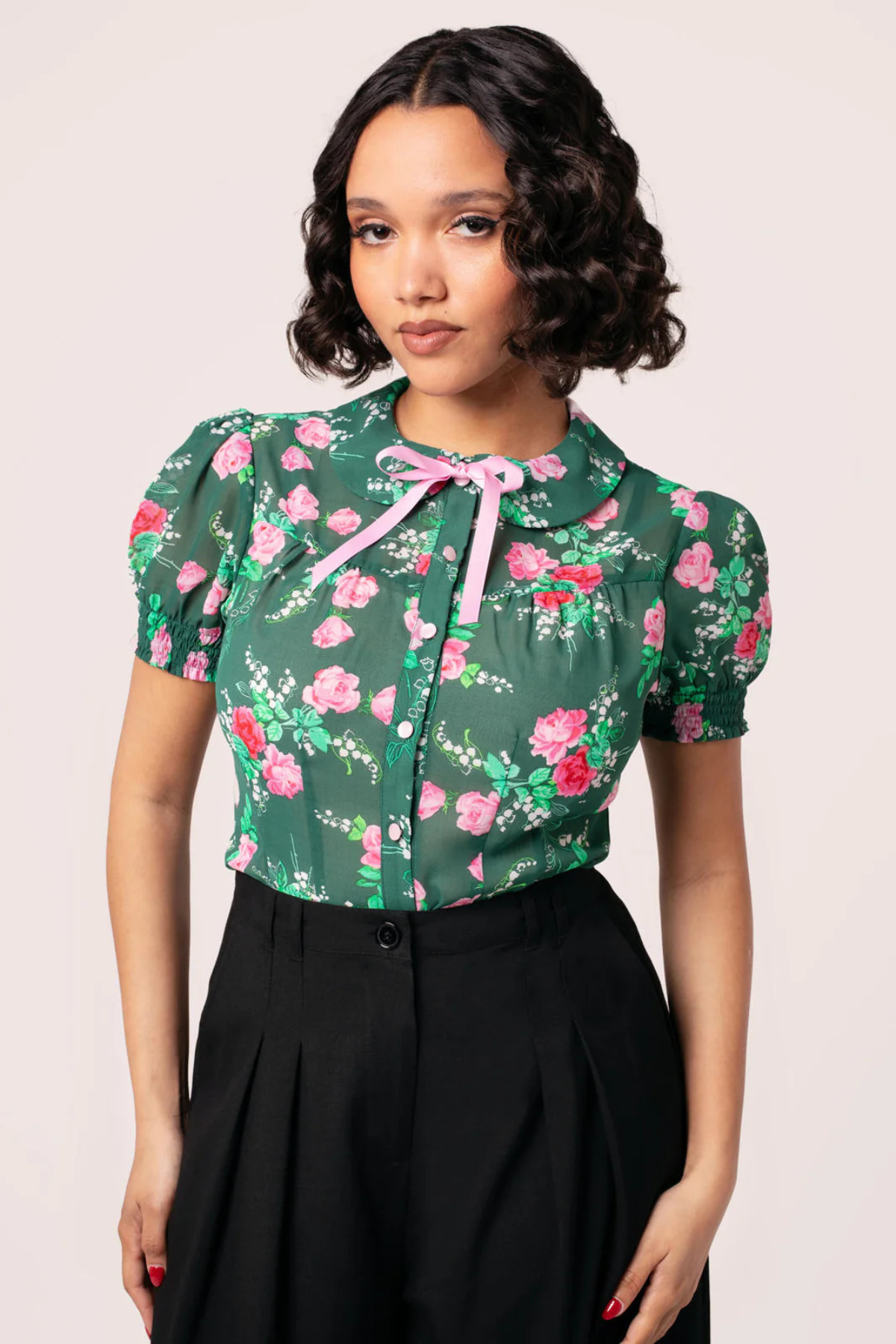 Model iført Hell Bunny Mabel Blouse – grøn bluse med blomsterprint og puffærmer i 50’er sti