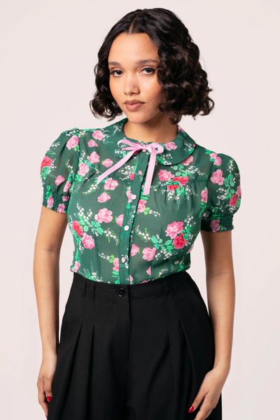 Model iført Hell Bunny Mabel Blouse – grøn bluse med blomsterprint og puffærmer i 50’er sti