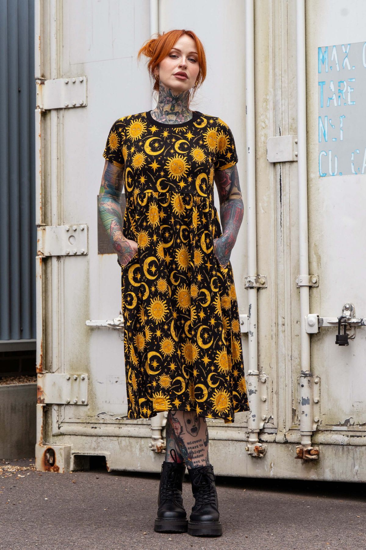Model står med hænder i lommerne i sort Rebel Romance kjole med sol og måne mønster.