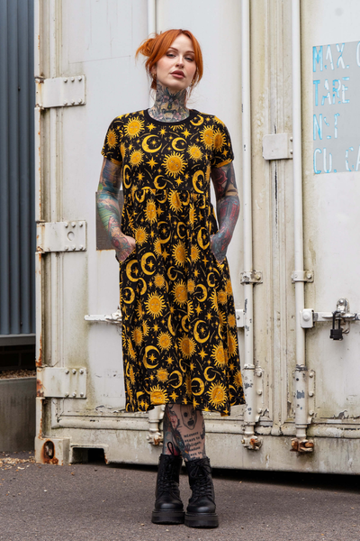 Model står med hænder i lommerne i sort Rebel Romance kjole med sol og måne mønster.