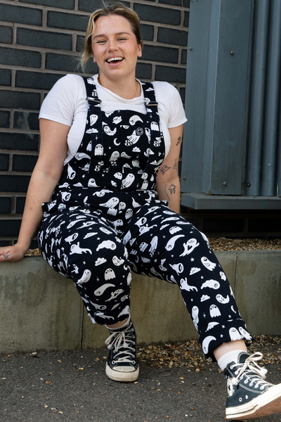 Model iført Rebel Romance Ghosties Dungarees siddende, smilende. Detaljeret visning af pasform og print.