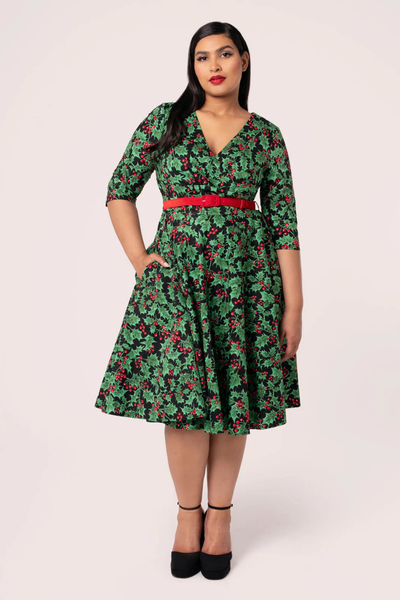 Model i Hell Bunny Nicole Dress – grøn julekjole med kristtorn og røde bær, taljebælte og 50’er swing-facon