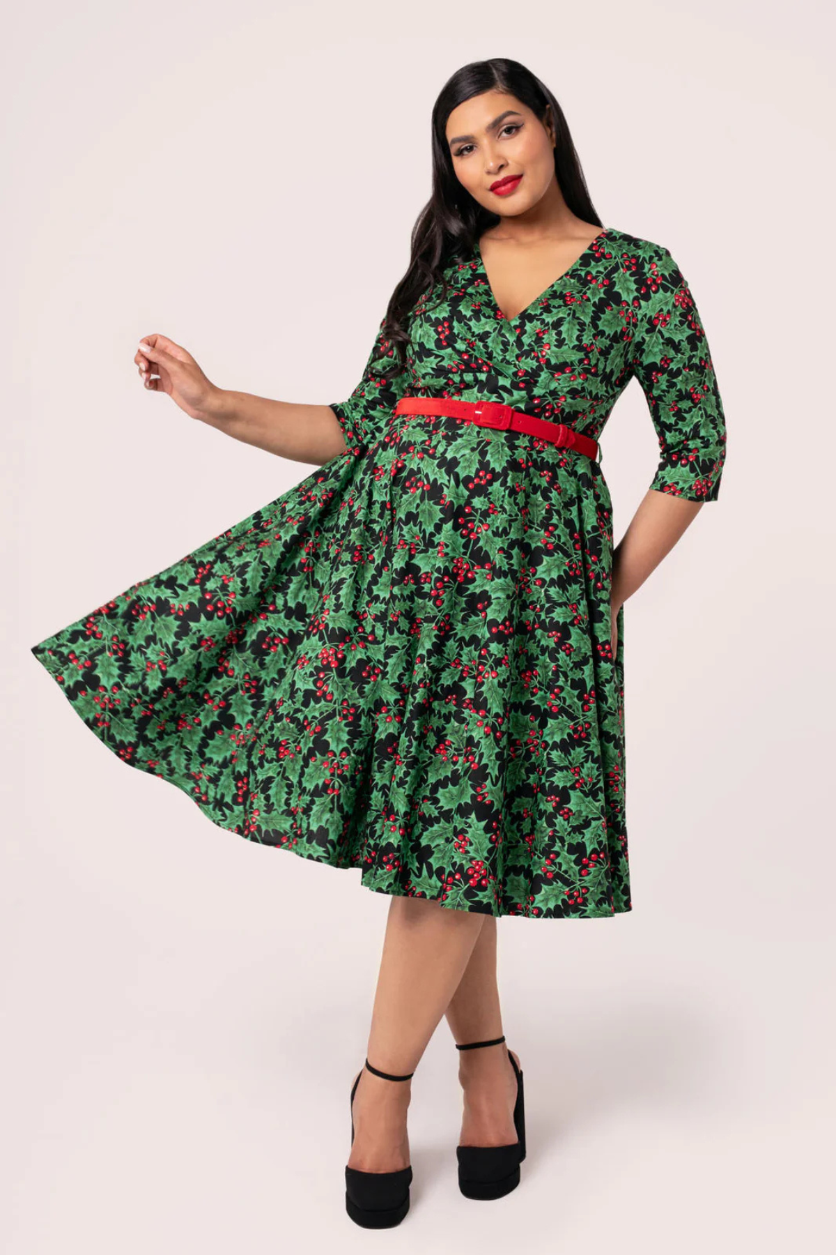 Hell Bunny Nicole Dress vist i bevægelse – grøn kjole med vintage holly print og rød velourbælte