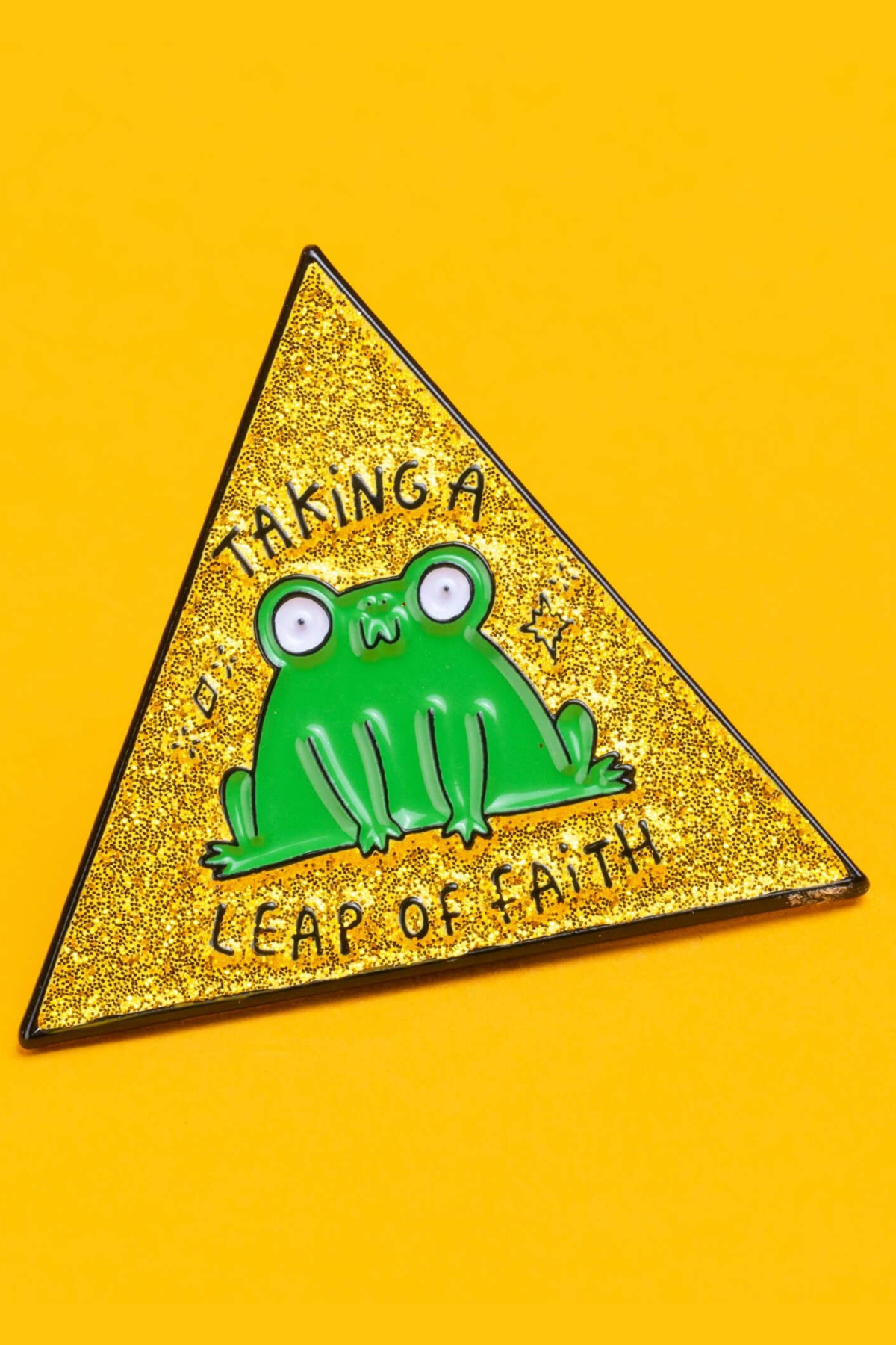 “Taking a Leap of Faith” frø emaljepin i gylden glitter trekant på gul baggrund