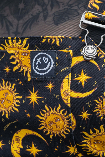 Close-up af Celestial Sun & Moon print – gule sole, måner og stjerner på sort baggrund.