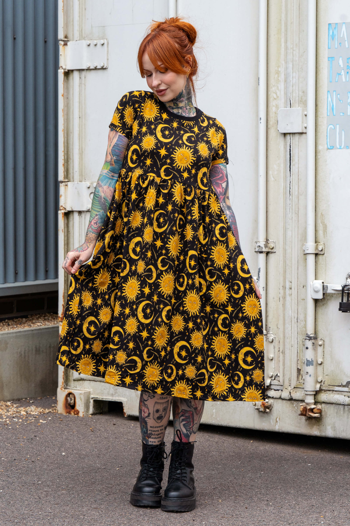 Model i sort kjole med gule sol og måne print fra Rebel Romance – kortærmet, løs pasform og lomme i siden.