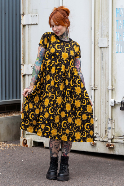 Model i sort kjole med gule sol og måne print fra Rebel Romance – kortærmet, løs pasform og lomme i siden.