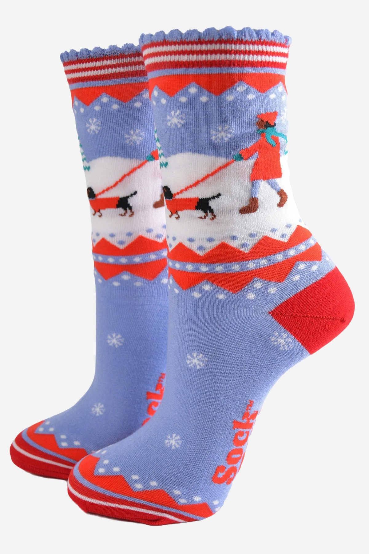 Blå og røde bambusstrømper fra Sock Talk med vintermotiv af kvinde der går en pølsehund i sneen