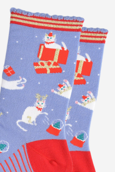 Nærbillede af julekat-design med gaveæske og snefnug på blå bambusstrømper