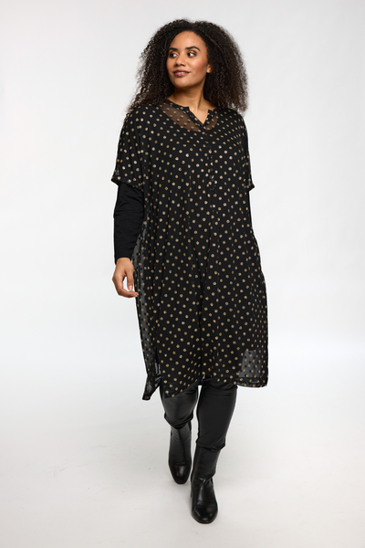 Model iført STUDIO Alma Dress i sort med guldprikker, set forfra.