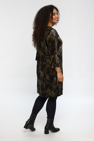 Model i STUDIO Helda Velourkjole set fra siden med fokus på kjolens fald.