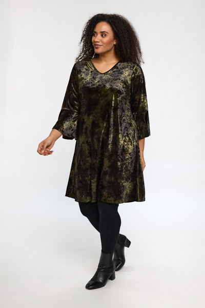 Model i STUDIO Helda Velourkjole bevæger sig i grøn velour med smuk glans.